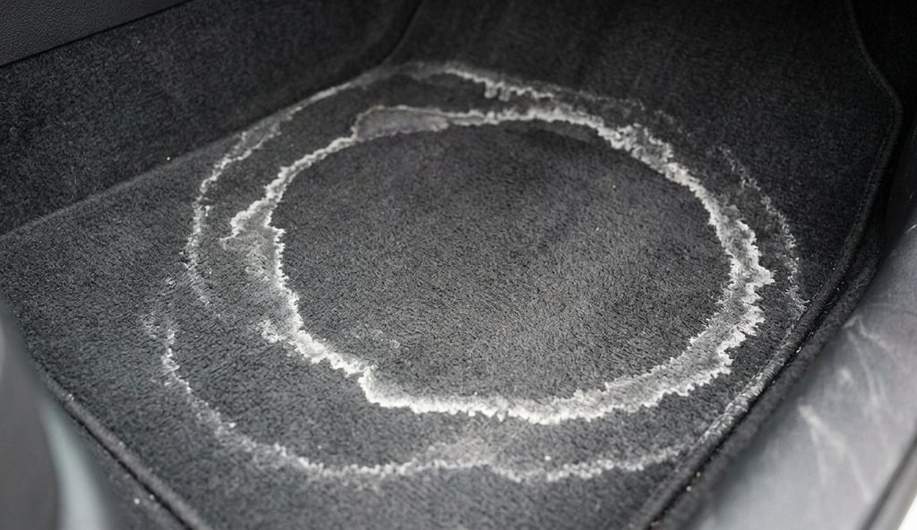 Cerco blanco de sal seca dibujado sobre la moqueta oscura del suelo de un coche